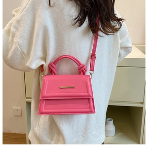 Detail of pink faux leather crossbody bag with gold metal trim and knotted strap detail