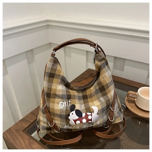 Detailed view of plaid wool tote bag with cartoon dog print and brown leather handles