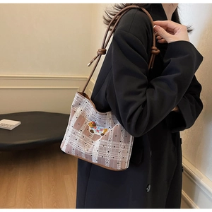 Détail du sac à carreaux avec bordures en dentelle et écusson brodé de chat