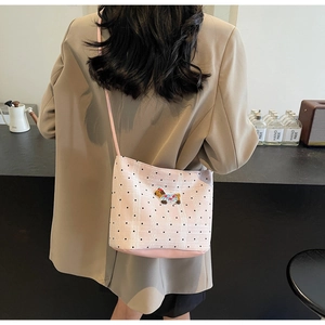 Détail du sac bandoulière rose avec pois, motif quadrillé et broderie de chiot