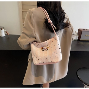Détail du sac à bandoulière rose à pois avec broderie de chien et sangle à nœuds