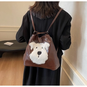 Detail of deep brown faux leather backpack featuring a white plush puppy patch