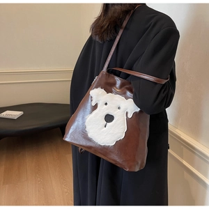 Detail of dark brown PU leather tote bag featuring a fluffy white dog plush applique
