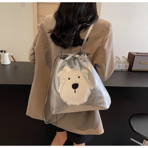 Detail of silver metallic bucket bag featuring white plush dog embroidery on the front