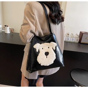 Detail of black glossy tote bag featuring a large white plush dog patch and side zipper