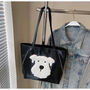 Detail of black faux leather tote bag featuring a white plush schnauzer dog patch