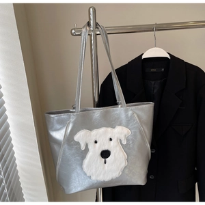 Detail of silver metallic tote bag with fuzzy dog patch hanging on metal hanger
