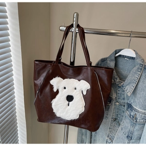 Detailed close-up of brown PU leather tote with plush dog patch and silver zipper accents