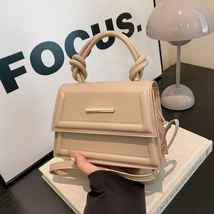 Chic beige crossbody bag with knotted handle and gold clasp on a minimalist background