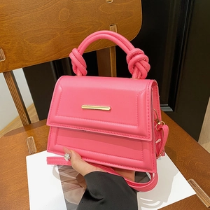 Minimalist bright pink square crossbody bag with dual knotted handle on wood chair