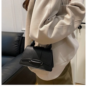 Détail du sac à main noir en cuir grainé avec fermeture à œillets métalliques unique