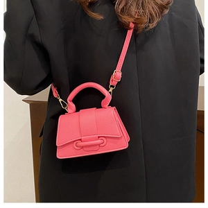 Mini sac bandoulière rose fluo avec texture cuir grainé et détails dorés sur veste noire