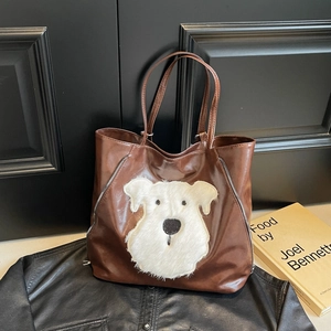Brown large capacity PU tote bag with plush dog patch on a leather jacket background