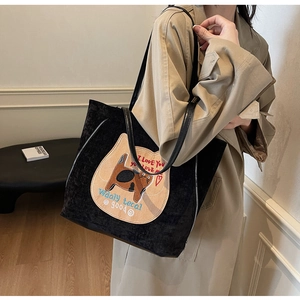 Détail du sac cabas en velours côtelé noir avec écusson chat et bandoulière en cuir