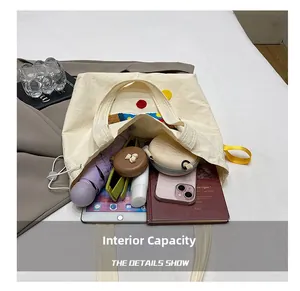 Détail du sac cabas en toile beige montrant sa grande capacité pour tablette et objets