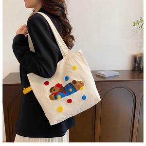 Détail du sac cabas en toile blanche avec motif de chien brodé et pois colorés