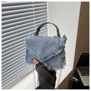 Détail du sac à bandoulière en denim bleu clair avec franges et chaîne en argent