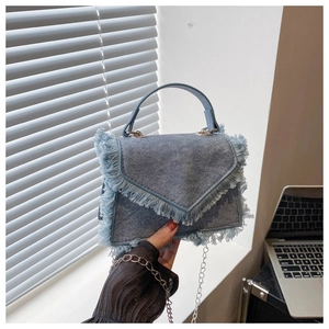 Détail du sac à bandoulière en denim bleu clair avec garniture à franges et chaîne argentée