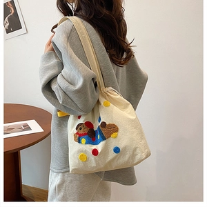 Détail du sac bandoulière en toile avec fermeture à cordon et broderie chien peluche