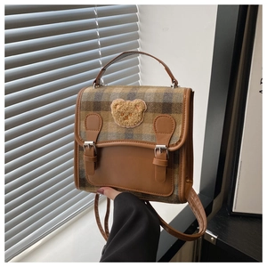 Detail of vintage plaid handbag featuring a cute teddy bear patch and brown PU straps