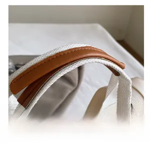 Detail of the corduroy tote bag handle with white webbing and brown leather wrap stitching