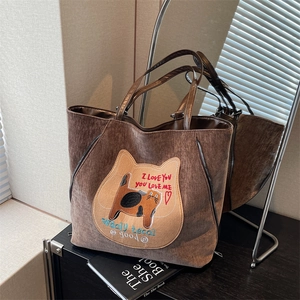 Sac cabas en velours côtelé marron avec écusson chat et doubles anses devant miroir