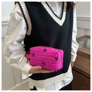 Detail of pink quilted makeup bag with black bow embroidery and side handle