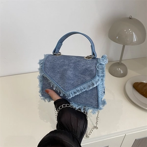 Sac à main en denim bleu délavé avec franges et chaîne dans un cadre cosy