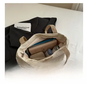 Vue détaillée de l'intérieur d'un grand sac cabas tressé beige contenant livres et portefeuille
