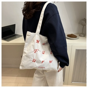 Detail of white corduroy tote bag with red letter embroidery and fashion text