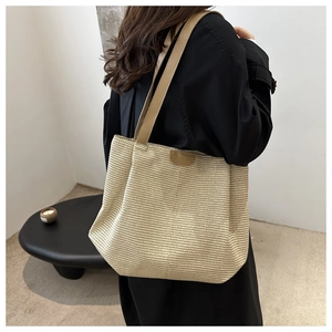 Vue détaillée du sac cabas en paille tressée avec anses en cuir et écusson logo