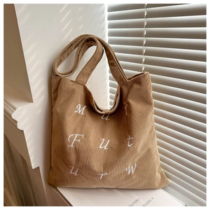 Detail of khaki corduroy tote bag showing white letter embroidery and soft ribbed texture