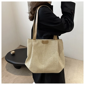 Détail d'un sac cabas tissé à la main avec texture beige et étiquette logo en cuir