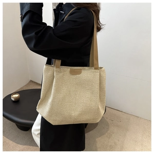 Détail de la texture tissée et de la bandoulière en cuir d'un grand sac cabas rayé