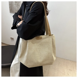 Détail de la texture paille tressée et des anses en similicuir d'un grand sac cabas