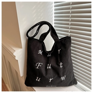 Detail of black corduroy tote bag showing textured fabric and white art embroidery