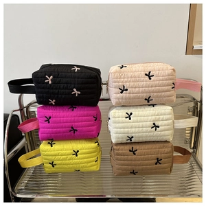Macro shot of six quilted cosmetic bags with bow embroidery and side strap handles