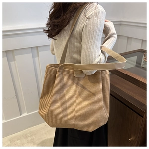 Détail du sac cabas tissé beige montrant la texture et le logo JUMAITU sur la bandoulière
