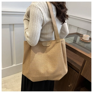 Détail du sac cabas tissé marron clair montrant l'anse en cuir et l'intérieur spacieux