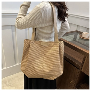 Détail d'un grand sac cabas tissé avec logo en cuir et bandoulière dans un café