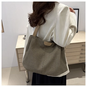 Détail du sac cabas tissé avec bandoulière en cuir kaki et étiquette logo de la marque