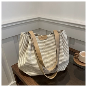 Gros plan sur la texture du sac cabas tissé avec logo en cuir et anses marron