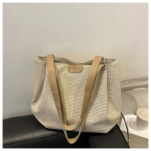Détail d'un sac cabas tissé avec étiquette en cuir sur un canapé en cuir noir