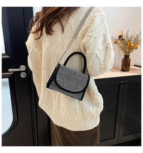 Model zeigt schwarze Handtasche mit Strassbesatz und silberner Kette für die Schulter