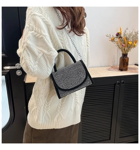 Detail von funkelnden Strasssteinen und Kettenriemen an einer schwarzen Luxus-Handtasche