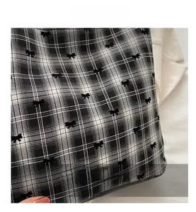Detailed view of black and white checkered fabric with 3D velvet bow accents on bucket bag