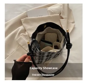 Detail display of the spacious interior capacity of this checkerboard bucket bag