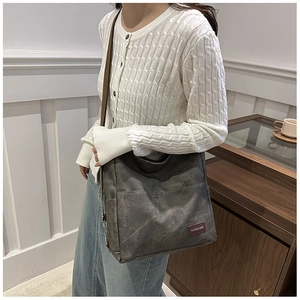 Detail of grey vintage canvas tote bag with dual front pockets on a casual model