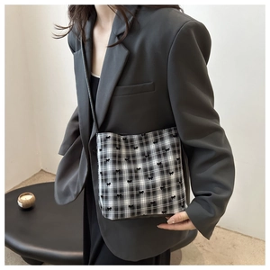 Detail of checkered crossbody bag with bow embroidery worn with a grey blazer outfit