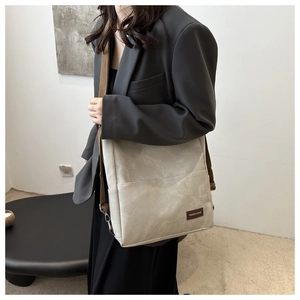 Detail of beige textured shoulder bag with fashion logo and brown fabric strap